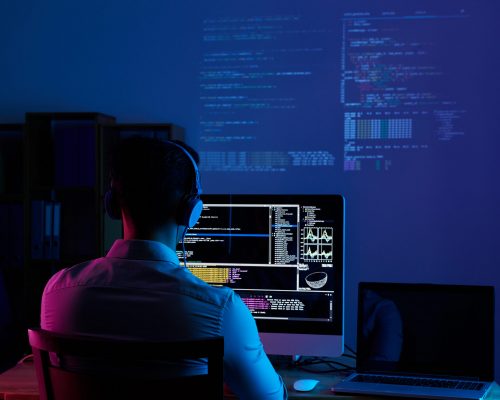 Developer working on code late at night, view from the back